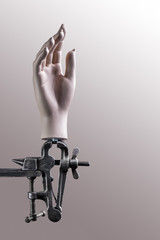 Mannequin hand fixed in a vise on a beige background
