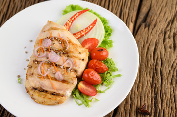 Fototapeta na wymiar Grilled chicken on a white plate with tomatoes, salad, onion, chili and sauce.