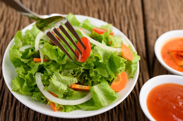 Salad on the plate with tomato on skewer fork.