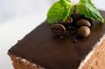 Chocolate cake on a white plate with coffee beans on a wooden table
