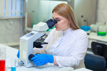 Laboratory assistant working with a microscope in a scientific laboratory.