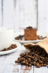 Coffee beans in hemp sacks on a white wooden table.
