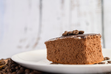 Chocolate cake on a white plate on a wooden table.
