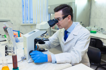 Scientist carries out scientific research looking through microscope in a medical laboratory.