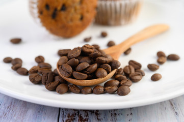Coffee beans on wooden spoon and Banana Cupcakes on a white wood table.