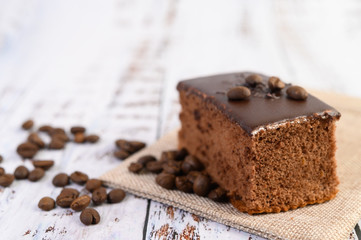 Chocolate cake on the sack with coffee beans on a wooden table.