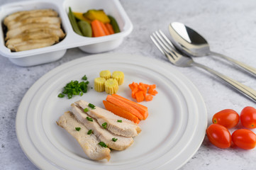 Steamed chicken breast on a white plate with spring onions and chopped carrots