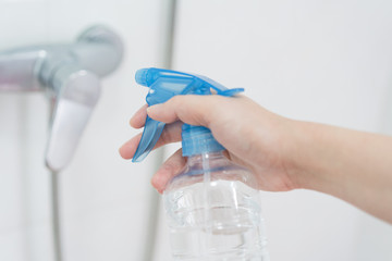 Hand holding disinfectant sprayer in cleaning faucet