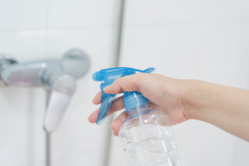 Hand holding disinfectant sprayer in cleaning faucet