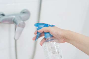 Hand holding disinfectant sprayer in cleaning faucet