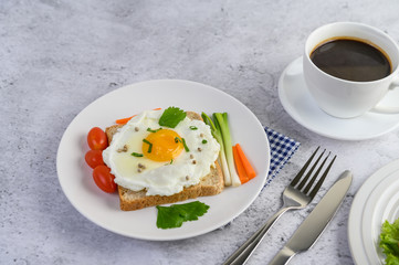 A fried egg laying on a toast, topped with pepper seeds with carrots and spring onions.