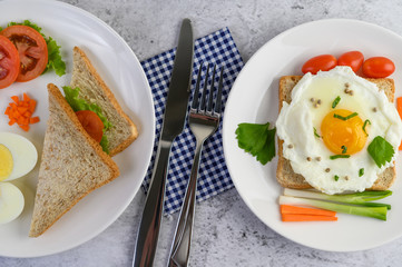 A fried egg laying on a toast, topped with pepper seeds with carrots and spring onions.