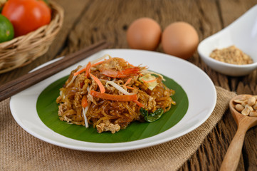 Padthai shrimp in a black bowl with eggs, Spring onion, and Seasoning on wooden table.