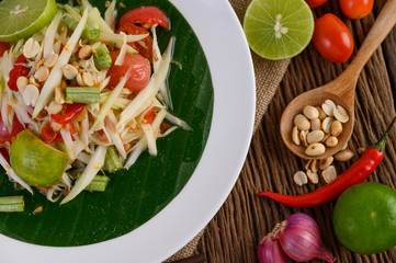 Papaya Salad (Som tum Thai) on a white plate on a wooden table.