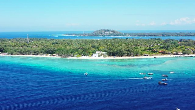 Lombok, Indonesia, Gilli islands surrounded by crystal clear turquoise sea water and deep sea ocean with boats. Luxury vacation background