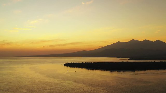 Romantic sunset over the Gilli Islands, Bali, Indonesia. Cinematic aerial seascape, golden colored sky mountains in the background.