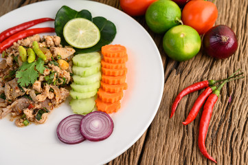 Spicy Minced Pork Salad on a white plate on wooden table.