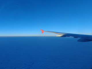 Fototapeta premium flying in a plane in the sky above the clouds on the wing at dawn aviation vacation