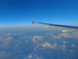 flying in a plane in the sky above the clouds on the wing at dawn aviation vacation