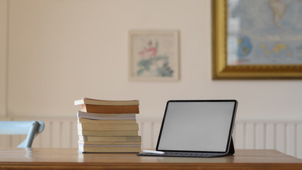 Close up view of workplace with mock up digital tablet and books on wooden desk