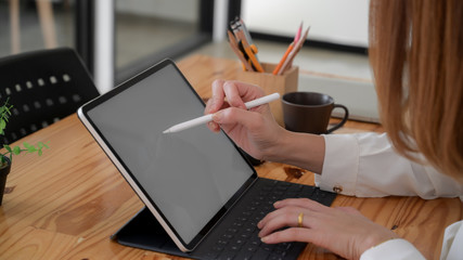 Side view of female freelancer drawing on blank screen tablet  while sitting in simple co working...
