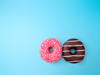 two pink and chocolate doughnuts on a blue background. the view from the top