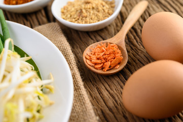 The seasoning is in a white spoon and eggs on a wooden table.