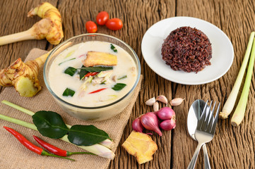 Tom Kha Kai in a bowl with kaffir lime leaves, lemongrass, red onion, galangal and chilli.