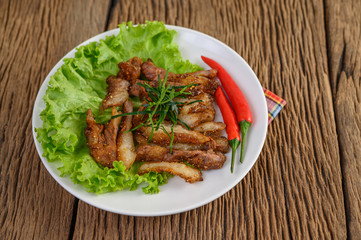 Grilled pork neck on a white plate on a wooden table
