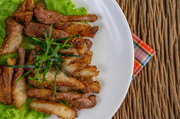 Grilled pork neck on a white plate on a wooden table