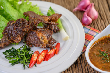 Beef fried Thai food on a white plate with spring onion, kaffir lime leaves, chilies, salad, red onions and tomatoes. Selective focus.