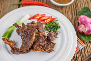 Beef fried Thai food on a white plate with spring onion, kaffir lime leaves, chilies, red onions and tomatoes. Selective focus.