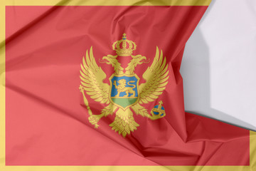Montenegro fabric flag crepe and crease with white space. A red field surrounded by a golden border; charged with the Coat of Arms.