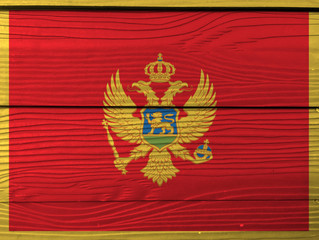 Montenegro flag color painted on Fiber cement sheet wall background. A red field surrounded by a golden border; charged with the Coat of Arms.