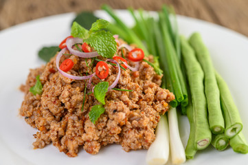 Spicy Minced Pork Salad on a white plate with lentils, kaffir lime leaves and spring onions.