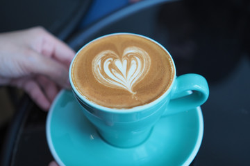 A cup of hot coffee with beautiful flower shape latte art on marble table background. Selective focus.