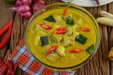 Green curry in a bowl with lime, red onion, lemon grass, garlic and kaffir lime leaves