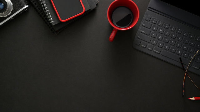 Stylish workplace with wireless keyboard, smartphone, copy space and coffee cup on black table