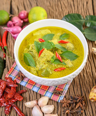 Green curry in a bowl with lime, red onion, lemon grass, garlic and kaffir lime leaves