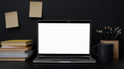 Close up view of trendy workplace with blank screen laptop on black table