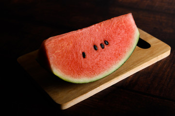 Cut watermelon in chopping boards on a wooden table.