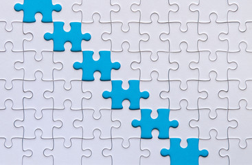Fototapeta premium Jigsaw puzzle white color on blue color background copy space for text,Top view