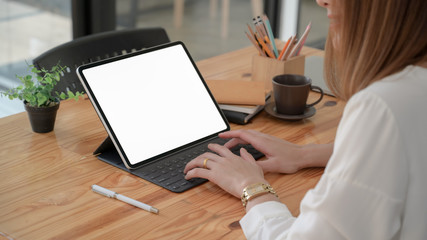 Cropped shot of freelancer typing on digital tablet  in modern co-working space