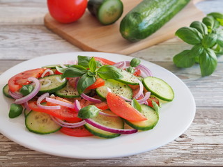 Healthy salad of fresh vegetables - cucumbers, tomatoes, onions, basil. Diet food.