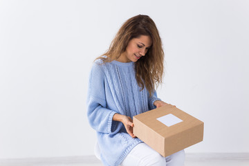 Online shopping, delivery and fashion concept - Woman sitting at home opening online clothing...