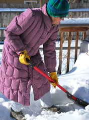 Female shoveling snow off patio deck.