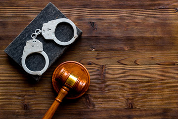 Arrest concept. Handcuffs near judge gavel on dark wooden background top-down copy space