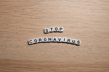 the word STOP CORONAVIRUS in white cubes on a light wooden background. Corona Virus design template