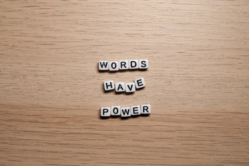 Word WORDS HAVE POWER in white cubes on light wooden background for your design templates
