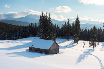 Charming snow-capped houses on a mountain Carpathian mountain valley, with magnificent views of peaks in winter.